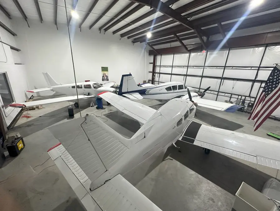 Interior of the Alpha Company Aviation flight school hangar with multiple training aircraft and the American flag