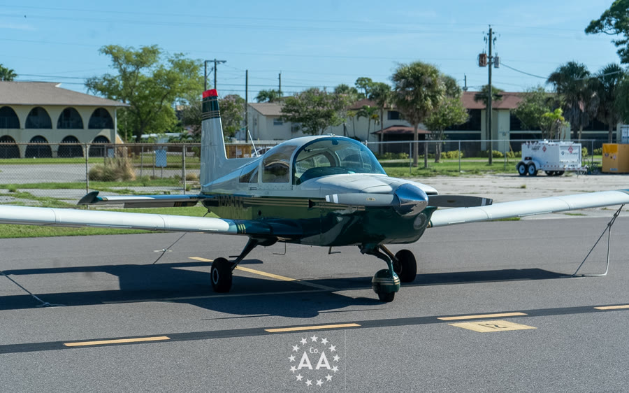 The Alpha Company Aviation Grumman AA-5B Tiger, a green and silver low-wing trainer, on the ramp at Venice Municipal Airport